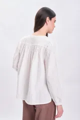 Blusa color crudo con textura, mangas largas abullonadas y cierre frontal con botones.