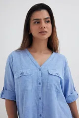 Camisa color crema de algodón con escote en V, mangas 3/4 con trabilla y dos bolsillos con solapa en el pecho.