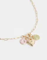 Collar corto dorado con cadena de eslabones y dijes colgantes de corazón dorado con incrustaciones de strass y esmalte verde, dona rosa con esmalte rosa y espiral verde con esmalte verde.