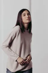 Sweater color crema de tejido de punto con hilos metalizados, corte relajado, hombros caídos y terminaciones clásicas.