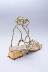 Sandalias doradas con tiras de cuerda para atar al tobillo.