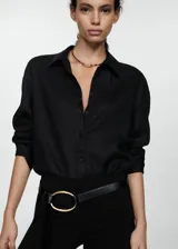 Camisa blanca de lino, de corte oversize, manga larga con puños abotonados, cuello camisero y cierre frontal con botones.