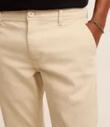 Pantalón de vestir marrón, de corte skinny, con bolsillos laterales y traseros. Se ajusta a la cintura con cinturón de cuero marrón.
