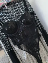 Body negro de tul elastizado con bordado de flores de lentejuelas, tiras regulables, copa y cierre invisible al costado.