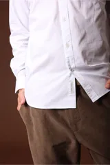 Camisa blanca de manga larga con cuello clásico y cierre frontal con botones.