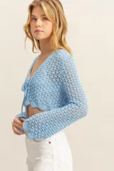 Crop top tejido a crochet color celeste, con escote en V y mangas largas acampanadas. Se ata en el centro del busto con cordones del mismo tejido.
