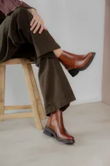 Bota corta color marrón con textura símil cuero de cocodrilo, caña baja, punta redondeada y taco cuadrado.