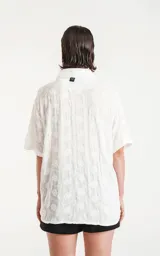 Camisa blanca con bordado de flores blancas, de manga corta y corte recto.