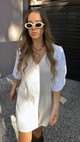 Vestido corto color crudo, con escote en V y mangas 3/4 abullonadas con detalles de calado.