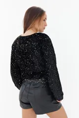Sweater negro de lentejuelas con cuello redondo y mangas largas.