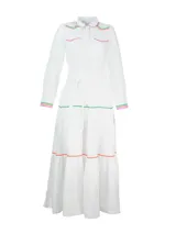 Vestido camisero largo de lino blanco con cuello camisero, cierre frontal con botones y cinturón de lazo. Presenta detalles de bordado ondulado en verde, naranja y rosa en cuello, bolsillos, puños y ruedo.