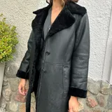 Chaqueta negra de cuero ovino con cuello y puños de piel sintética.