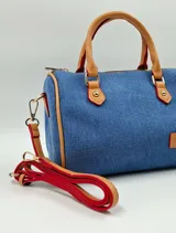 Cartera tipo bowling de jeans azul con detalles en cuero sintético color camel. Incluye llavero de peluche y dije de flor.