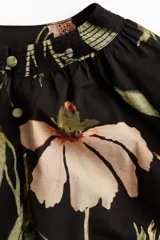 Blusa oversized de algodón y viscosa con estampado floral, cuello mao, abertura frontal con botones forrados, mangas globo largas de corte raglán con puños finos abotonados y bajo levemente redondeado.