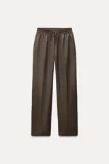 Pantalón de tiro medio color marrón, con cintura elástica ajustable con cordones, bolsillos delanteros y traseros, raya planchada y pierna recta.