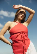 Top de lino color rojo con escote halter cruzado y detalle de lazo para atar en la cintura. Presenta un diseño con terminación en punta tipo pañuelo y espalda descubierta.