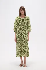 Vestido midi holgado con estampado de hojas en tonos verde y beige, cuello redondo con abertura en V y botones, y mangas 3/4 abullonadas.
