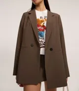 Blazer de mujer color marrón, de corte sastre alargado, con solapa ancha, cierre de doble botonadura y bolsillos tipo cuchillo.