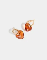 Aros dorados tipo argolla con dije de corazón de resina color naranja.