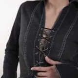 Camisa de jean color negro con efecto lavado, de manga larga con puños acampanados y cierre frontal mediante cordones trenzados. Presenta costuras a la vista en color blanco.