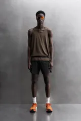 Pantalón corto deportivo color marrón oliva, con cintura elástica ajustable con cordón, bolsillos frontales y bolsillo trasero con cierre. Presenta forro interior y detalle de logo estampado en la pernera.