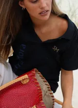 Polo shirt negra con logo bordado en dorado y estampado en azul.