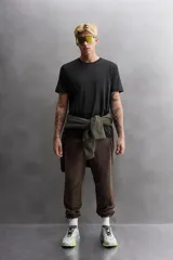 Pantalón de jogging color marrón oscuro, corte regular fit, confeccionado en tejido técnico ligero y elástico. Cuenta con cintura elástica ajustable con cordón, bolsillos frontales con cierre de cremallera, bolsillo trasero con cierre de cremallera oculta en costura y bajo ajustable con elástico.