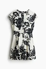 Vestido corto de algodón color blanco con estampado floral negro, escote redondo, manga japonesa, botonadura frontal y falda acampanada con pinzas en la cintura.
