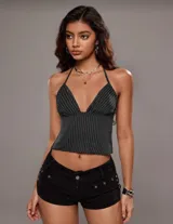 Top halter negro con rayas verticales blancas, escote en V pronunciado y espalda descubierta.