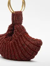 Bolso de mano tipo clutch, color verde, con abalorios tejidos en tricot. Tiene un compartimento con cierre de cremallera y cierre magnético. El asa de mano es metálica con el logo grabado.