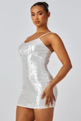 Vestido corto de fiesta color blanco, con lentejuelas brillantes, escote redondo y breteles finos.