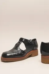 Zapato guillermina de cuero vacuno charol color negro, con suela de goma color marrón.