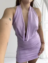 Vestido corto lila con escote halter y espalda descubierta. Diseño drapeado y ajustado al cuerpo.