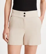 Bermuda blanca de poliéster con cintura elástica, cierre con cremallera y botones, y bolsillos laterales.