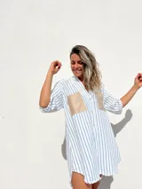 Camisola a rayas verticales azules y blancas, con cuello en V, mangas 3/4 y dos bolsillos cuadrados de gamuza color beige en el pecho.