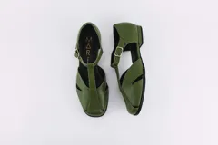 Zapatos bajos rojos de cuero, con puntera redondeada y tira central con hebilla. Presentan aberturas laterales.