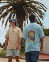 Remera celeste de manga corta con cuello redondo y estampado de tres hongos rojos con lunares blancos y la palabra 'Tuya' debajo.