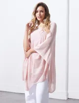 Poncho blanco de tejido calado con lurex, terminación asimétrica y cuello redondo.