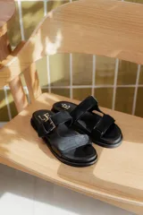 Sandalias negras de cuero con doble tira, una ancha con hebilla y otra fina.