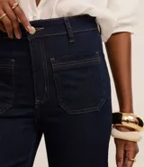 Pantalón de jean azul oscuro, de corte recto y tiro medio. Presenta bolsillos delanteros con costuras contrastantes y cierre frontal con botón y cremallera.