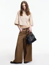 Camisa cropped color beige con botones en la parte delantera y mangas 3/4 con botones.