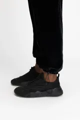 Pantalón jogger negro de terciopelo con cintura media ajustable con cordón, bolsillos laterales tipo cargo y puños elásticos.