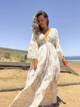 Vestido largo color crudo con estampado dorado, escote en V y mangas acampanadas.