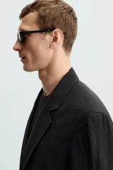 Blazer negra relaxed fit confeccionada en tejido fluido con mezcla de lyocell. Cuello con solapas de muesca y manga larga. Bolsillos de solapa en cadera. Detalle de bolsillo interior. Cierre frontal de botonadura.