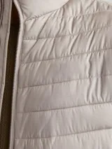 Campera puffer gris de manga larga con cuello alto y cierre frontal con cremallera.