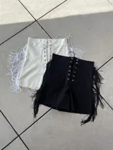 Short blanco de bengalina elastizada con cordones cruzados en la parte delantera y flecos en los laterales.