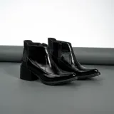 Botas cortas de cuero vacuno negro charol, con cierre lateral YKK, taco de madera foliado en cuero de 6cm y suela de goma.