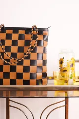 Bolso tipo tote de cuero tejido a mano con diseño a cuadros en color negro y tostado.