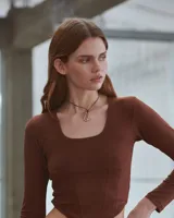 Collar con dije irregular dorado y cordón marrón ajustable.