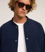Campera bomber marrón de terciopelo pana con cuello redondo, cierre con botones a presión, bolsillos laterales, puños y cintura elastizados.